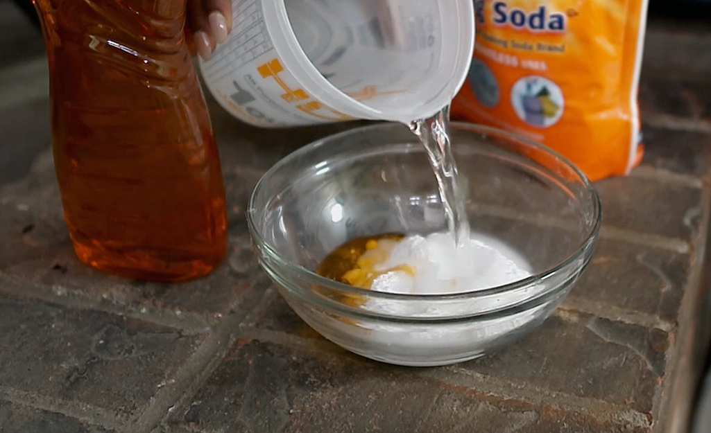 A person pours vinegar into a bowl of baking soda.