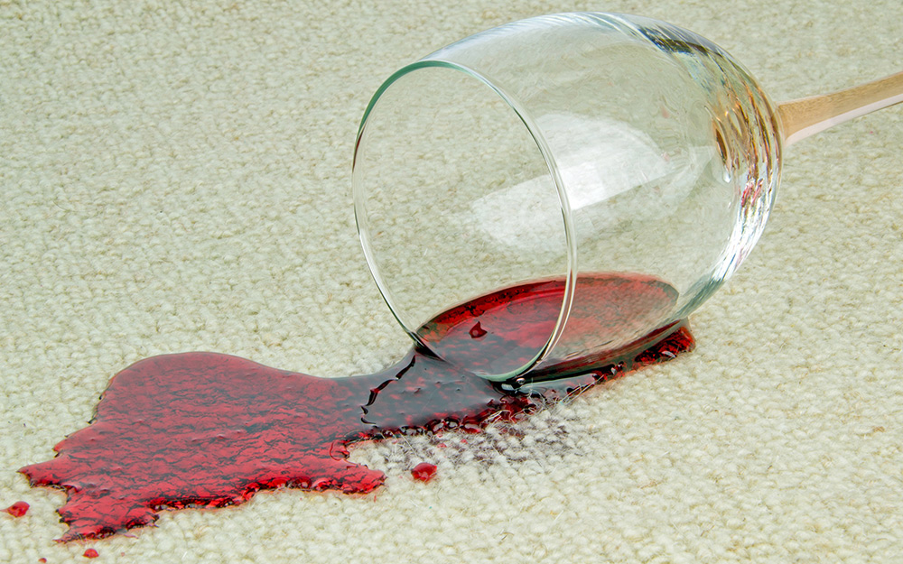 A glass of red wine is spilled on carpet. 