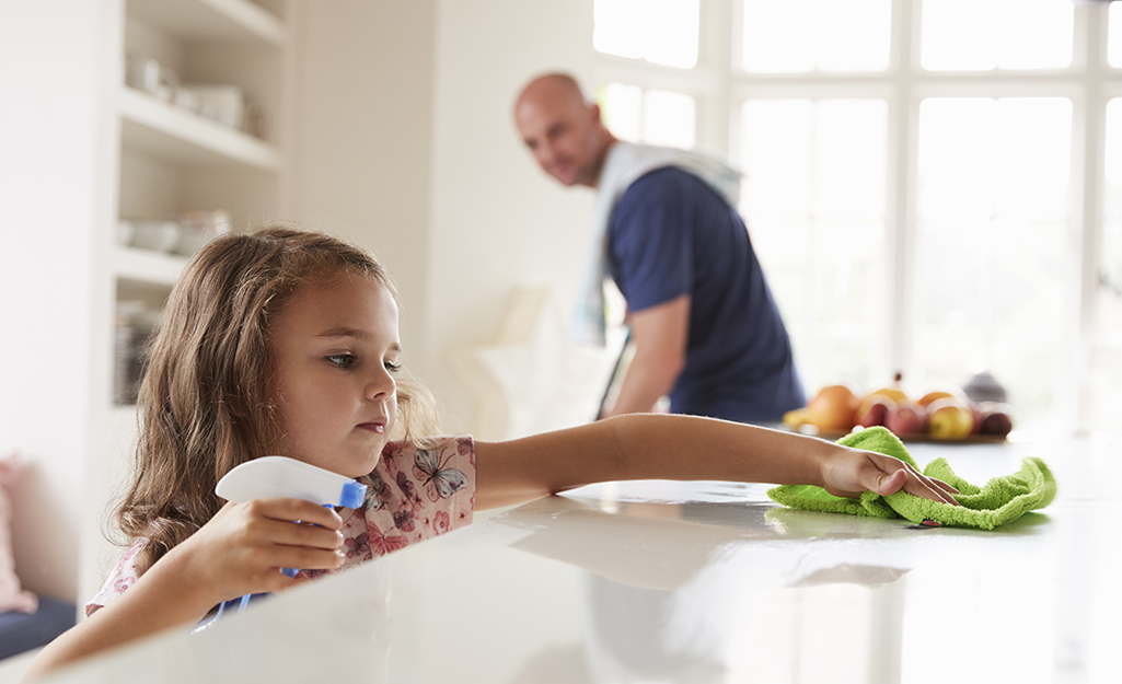 A child helping clean a kitchen counter. A child helping clean a kitchen counter.