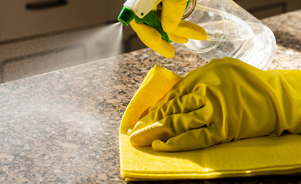 Person wiping granite countertop.