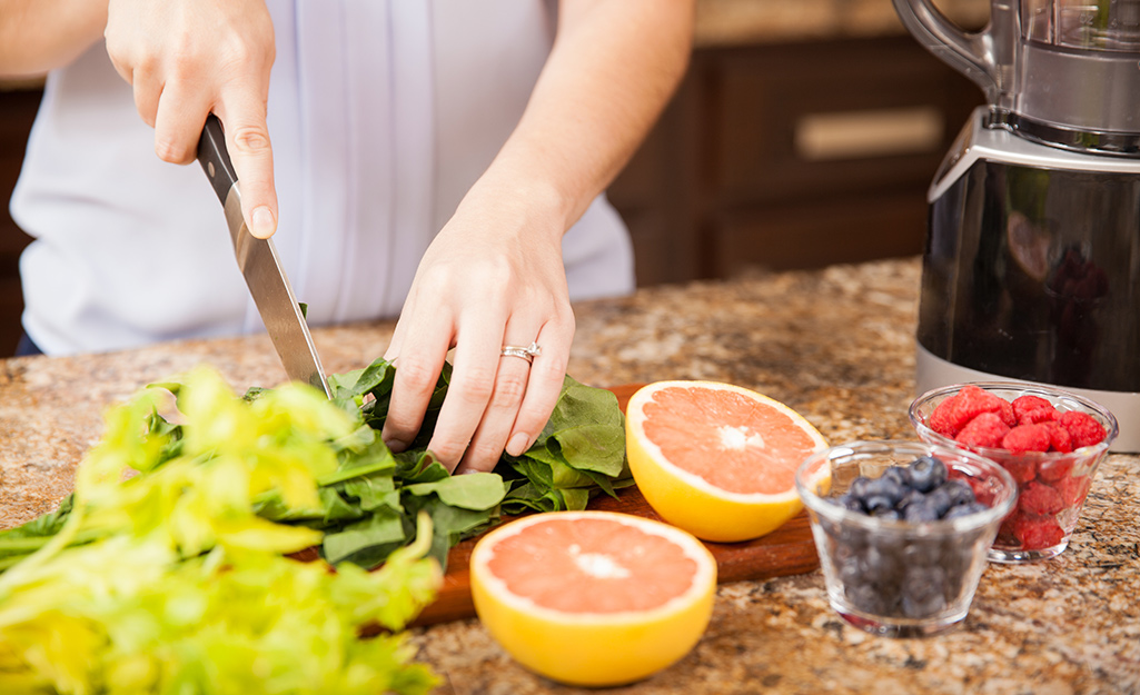 Someone making fruit salad on top of a clean kitchen countertop.