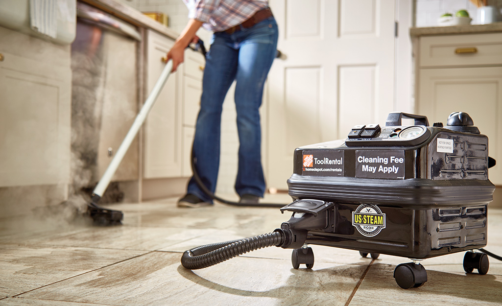 Someone using a steam cleaner to clean grout on a filed floor.