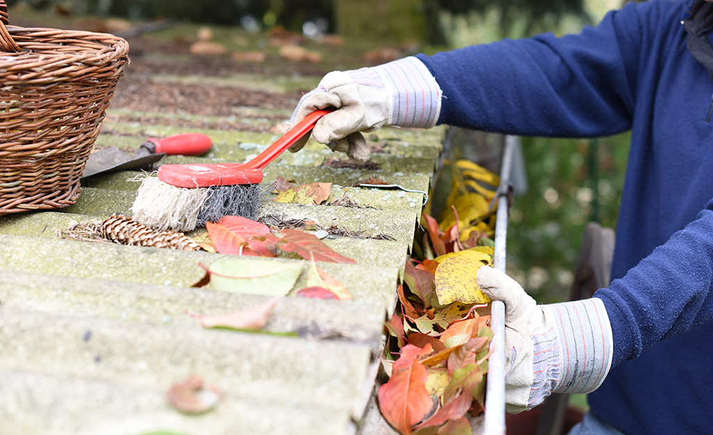 A person cleaning leaves from gutters.