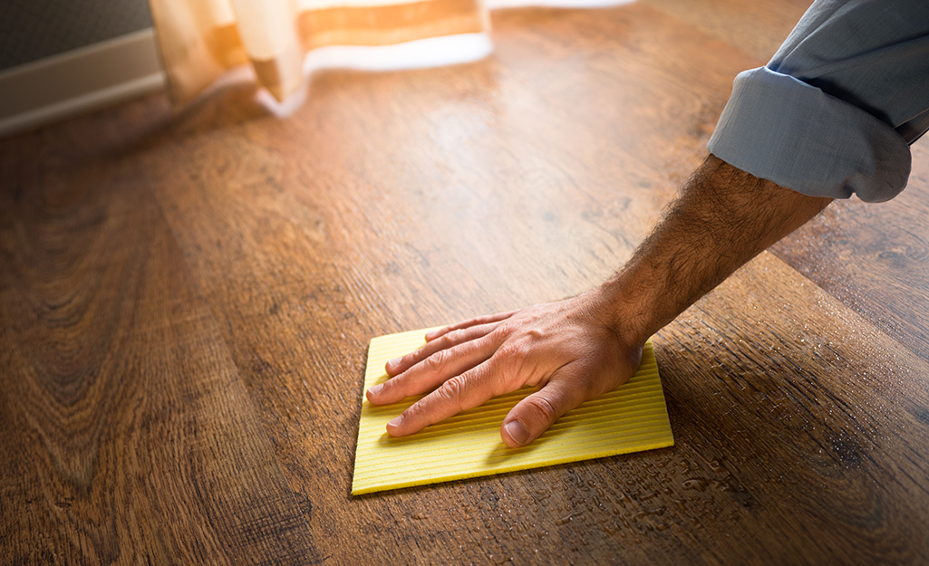 A person buffing out scratches on a wood floor.