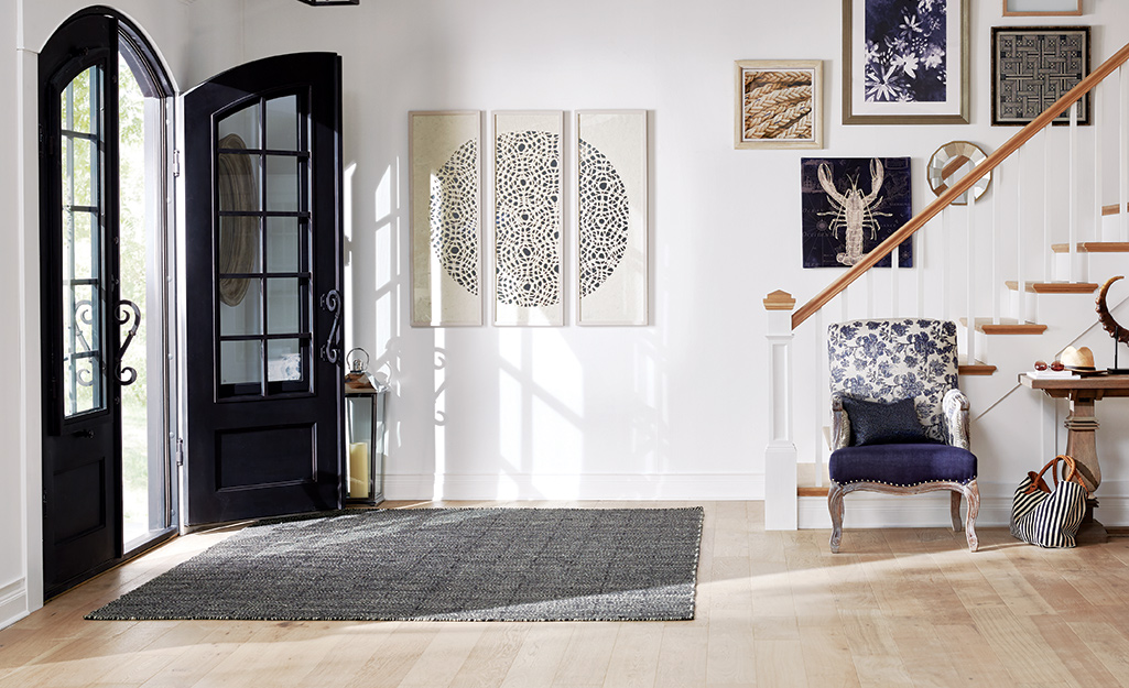 A rug covers the hardwood floor between the entrance and a staircase.