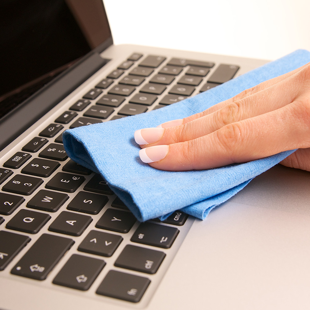 A person wiping a laptop keyboard with a microfiber cloth.
