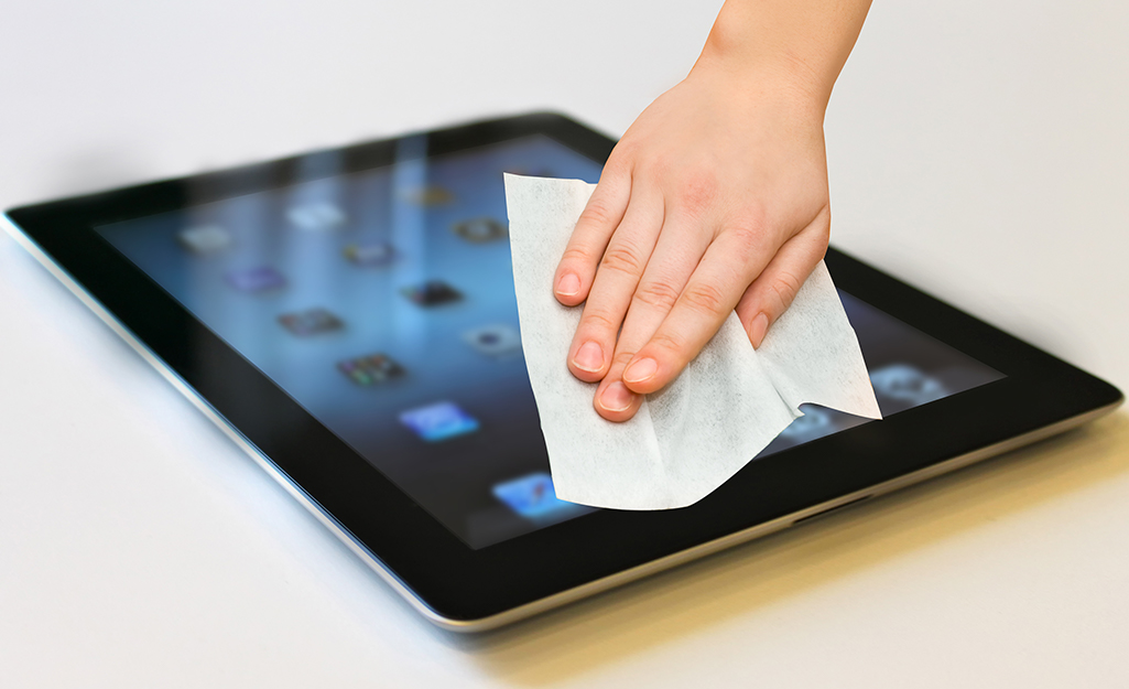 A person using a microfiber cloth to clean a tablet screen.