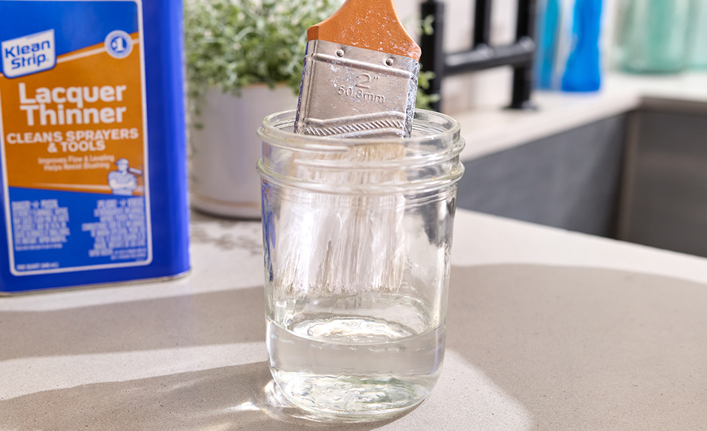 Person using solvent to clean a paint brush.