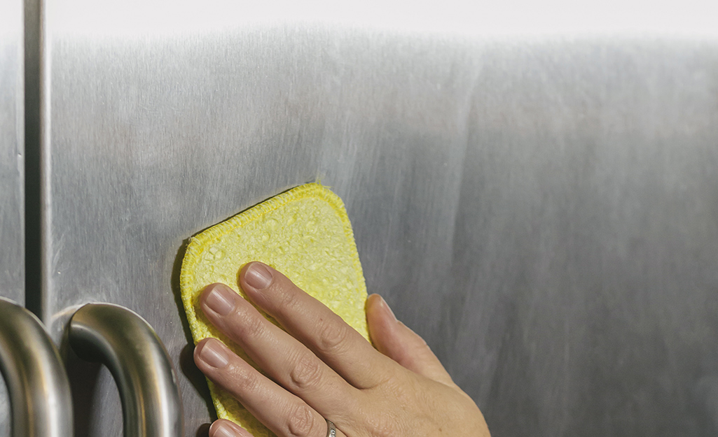 Person gently buffing stainless steel with a dry sponge.