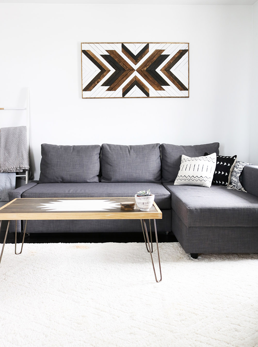 A room with a gray sectional sofa and a clean white rug.