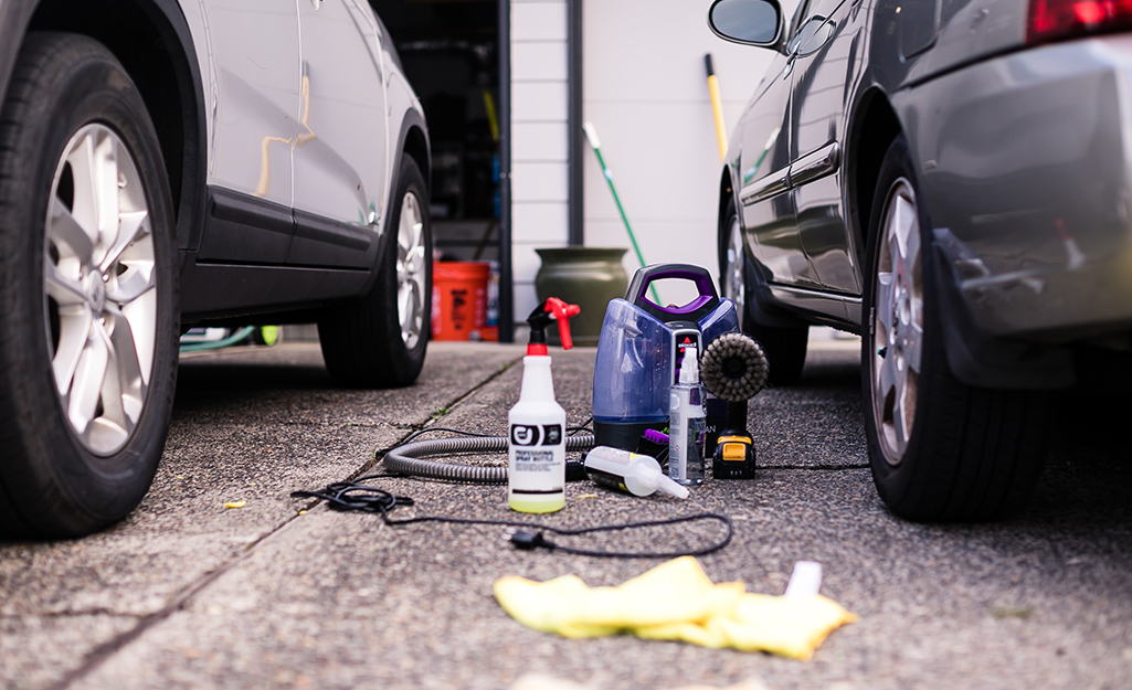 Car detailing supplies sit between the rear tires of two vehicles parked side by side.