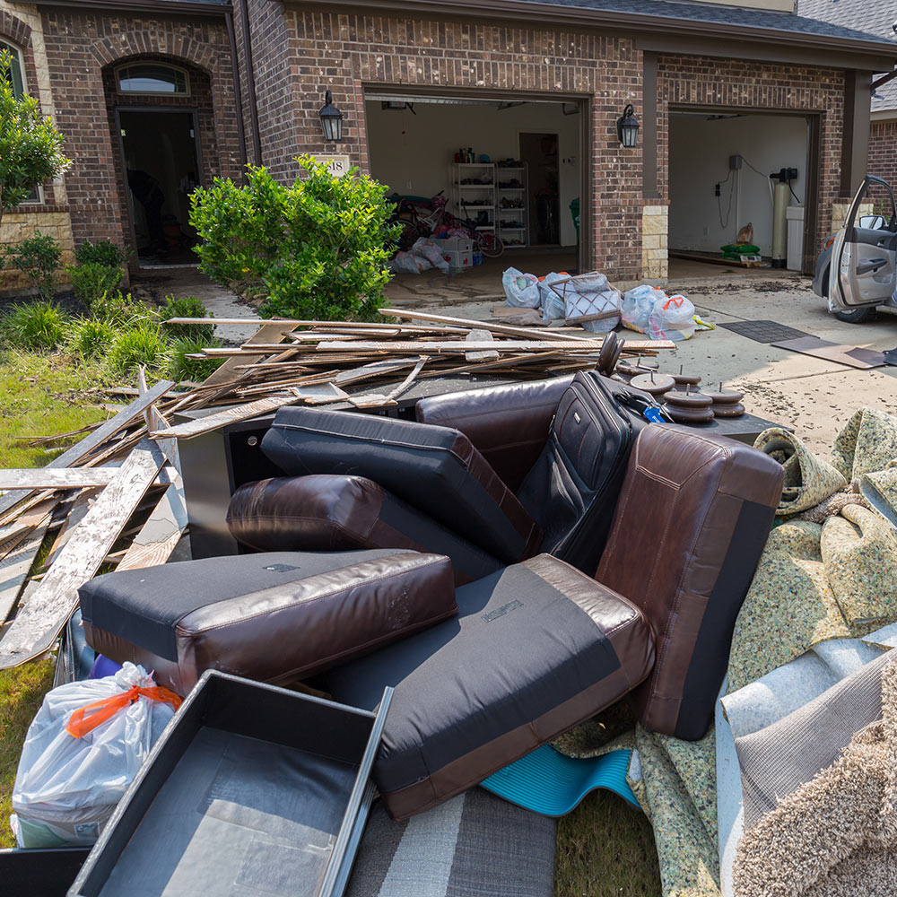 Discarded furniture and carpet outside a home after a flood.
