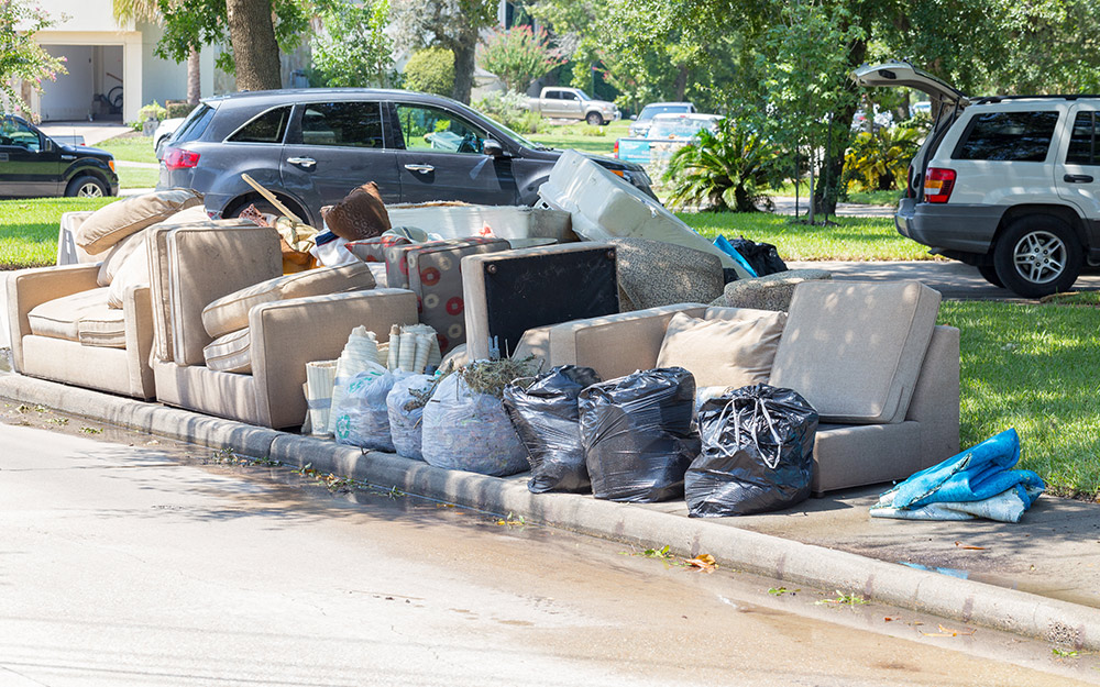 Furniture and other belongings damaged by a flood sitting on a curbside.