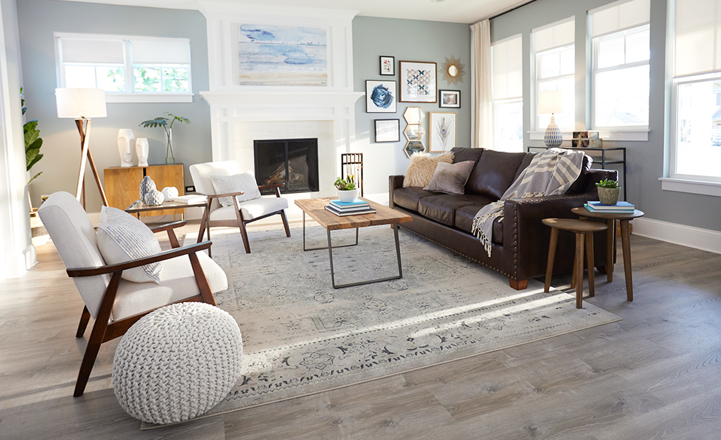 An airy living room has a large rug protecting vinyl plank flooring.