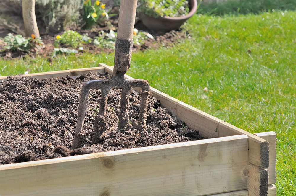 person using a garden fork to stir up compost person using a garden fork to stir up compost