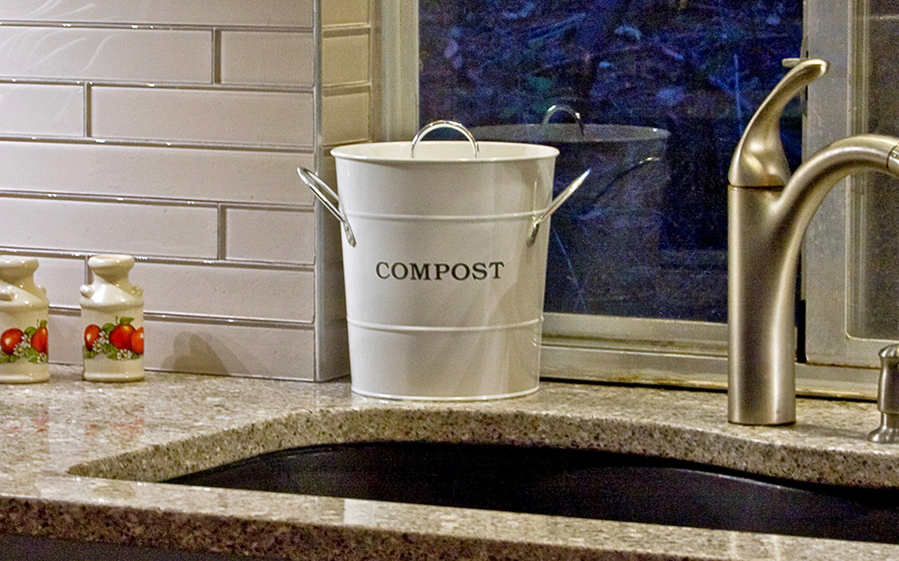 compost pail sitting on a countertop next to kitchen sink compost pail sitting on a countertop next to kitchen sink