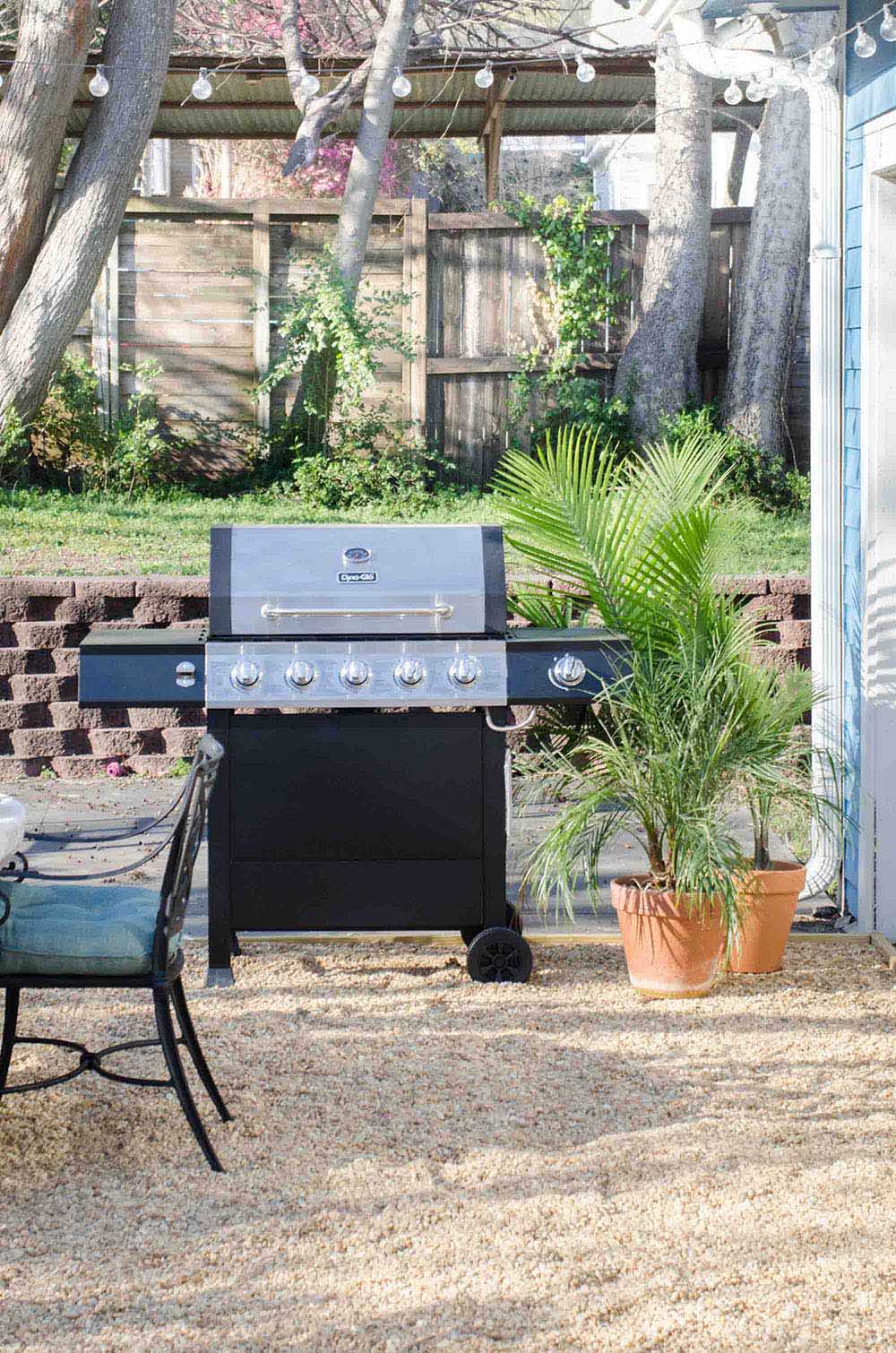 A grill sitting on a gravel patio.
