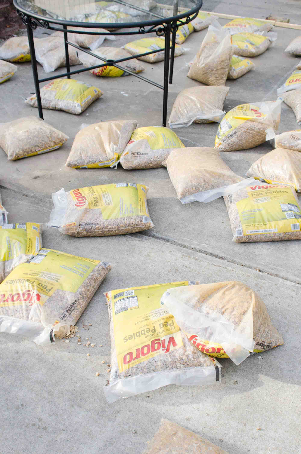 A concrete patio with bags of Vigoro pea pebbles laid out.