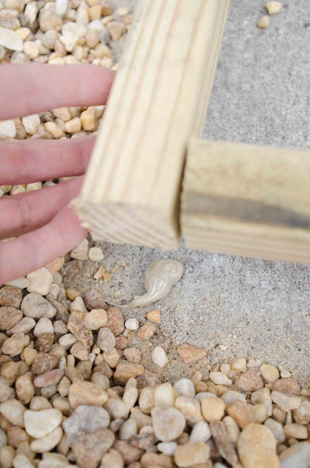 Two connected pieces of wood are being laid on a concrete floor with adhesive.