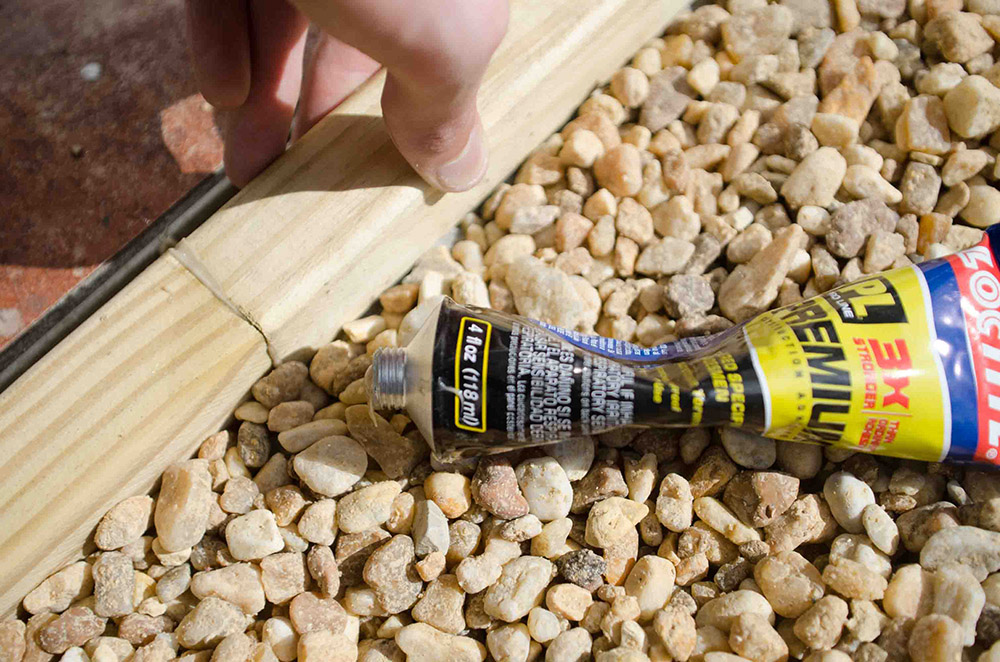 A bed of pea pebbles with a tube of Loctite premium construction adhesive.