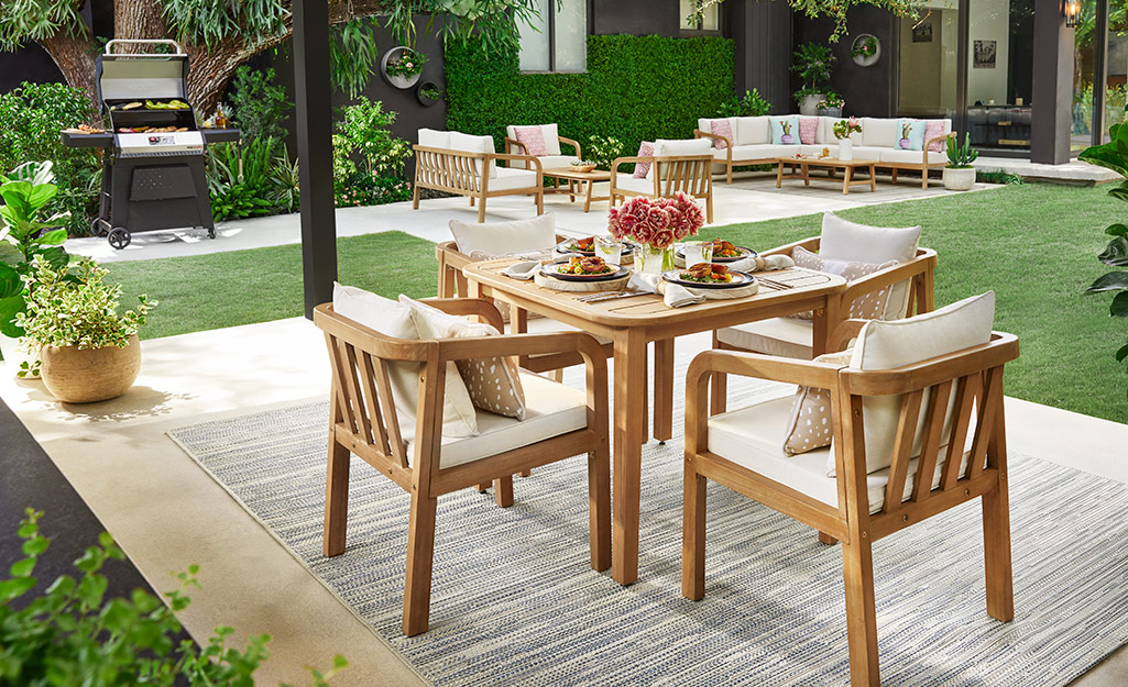 Outdoor dining set on a patio with a grill
