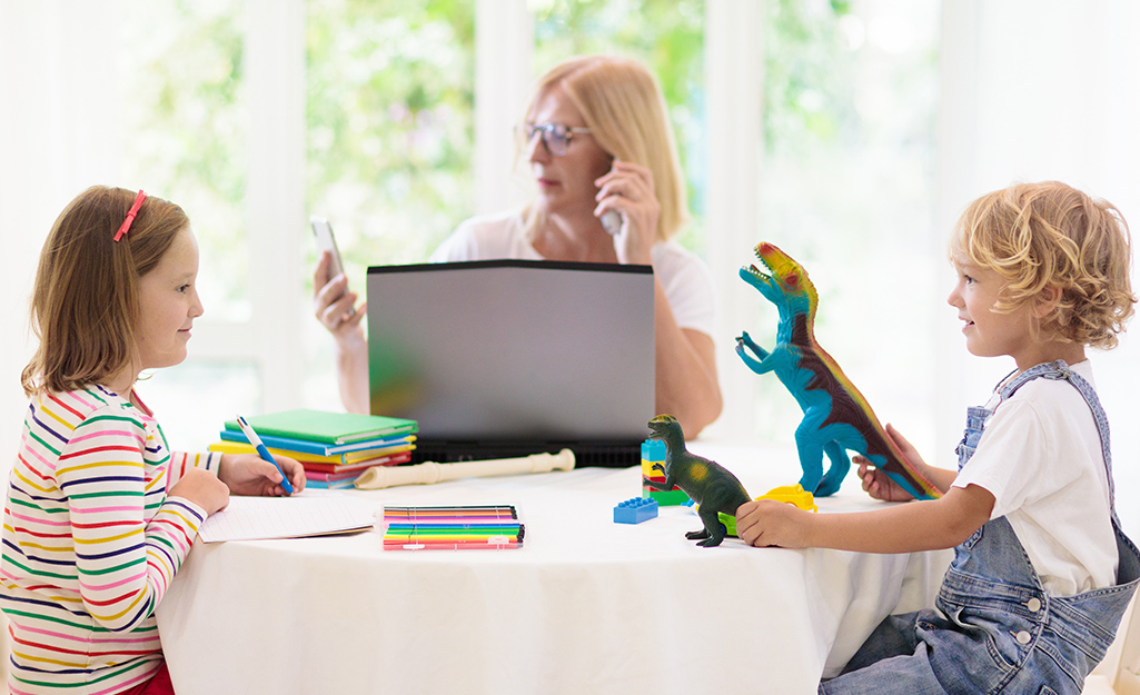 A woman with a laptop sitting at a table with two small children with learning tools. A woman with a laptop sitting at a table with two small children with learning tools.
