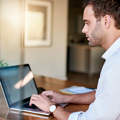 A man with a laptop at a dining table home workspace. A man with a laptop at a dining table home workspace.