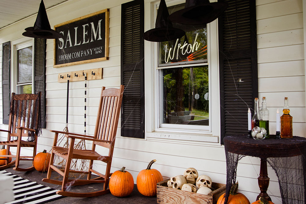 A front porch decorated for Halloween with pumpkins, skulls, and witch hats.