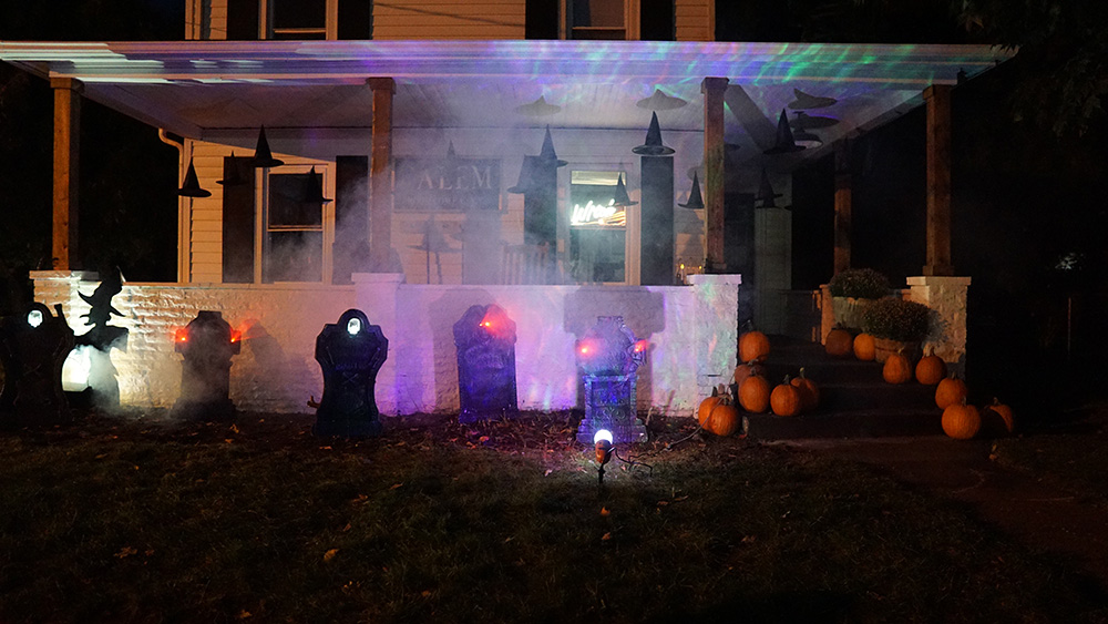 A home decorated for Halloween is lit up at dark by lights.