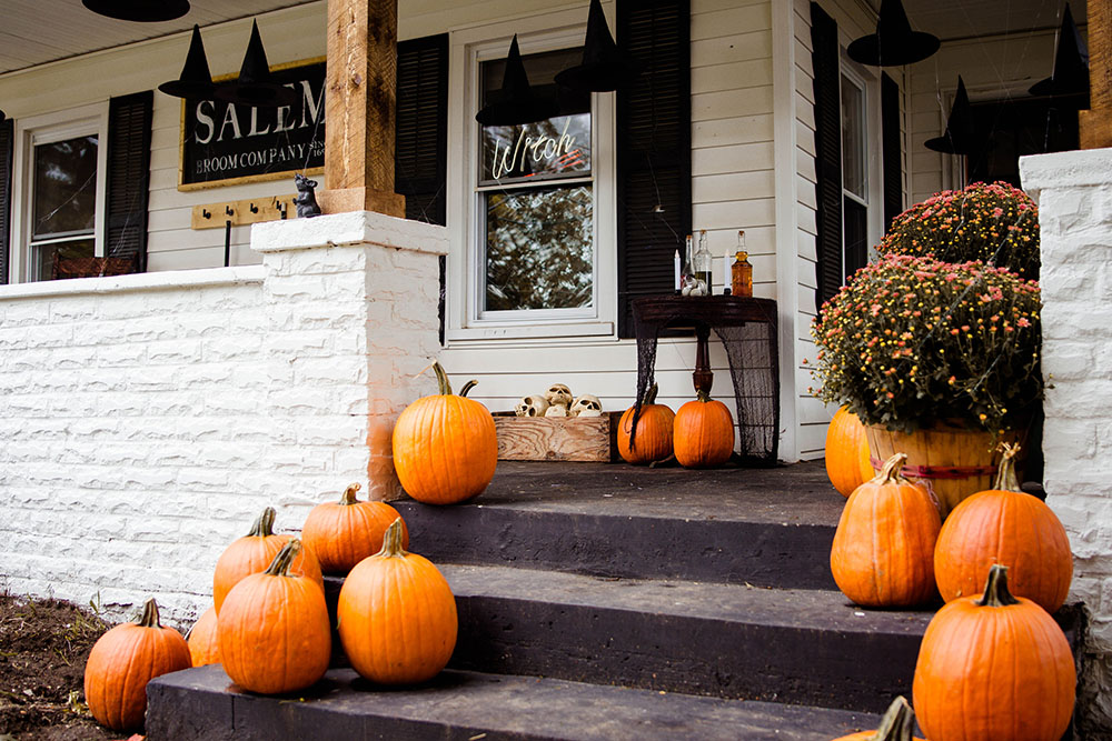 Mums and pumpkins decorate a white brick entryway.