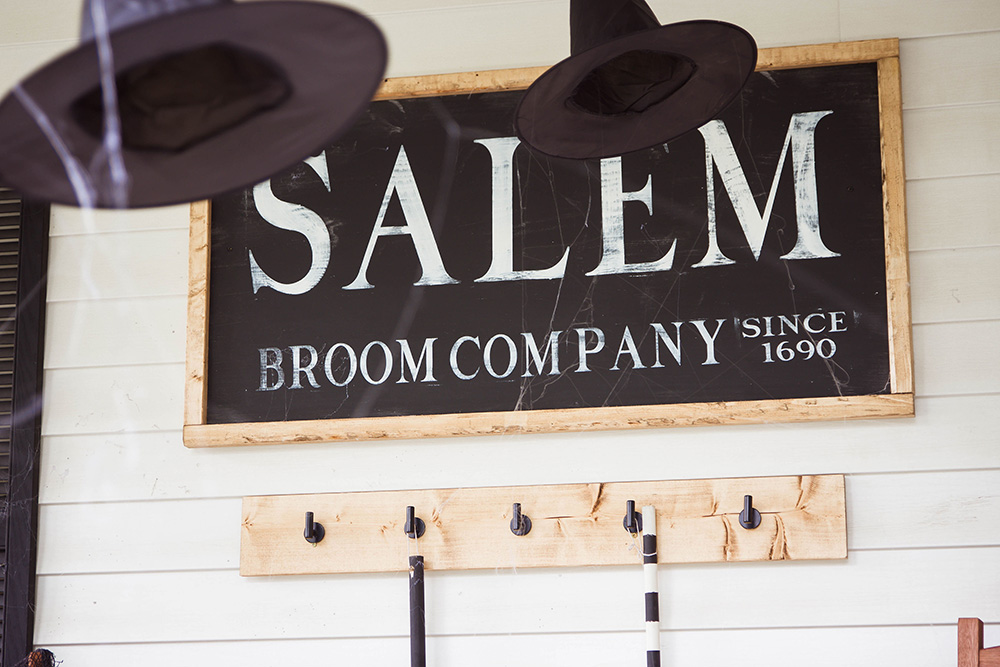 A white, black, and wooden Salem Broom Company sign.
