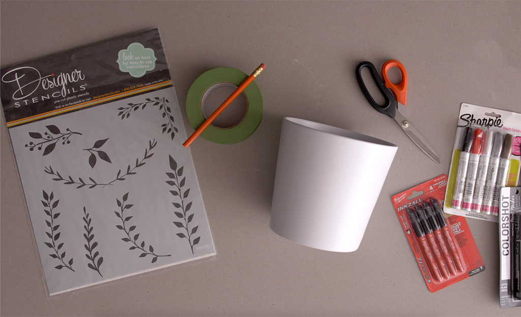 Stencils, markers, a plant pot and other supplies gathered on a table. Stencils, markers, a plant pot and other supplies gathered on a table.