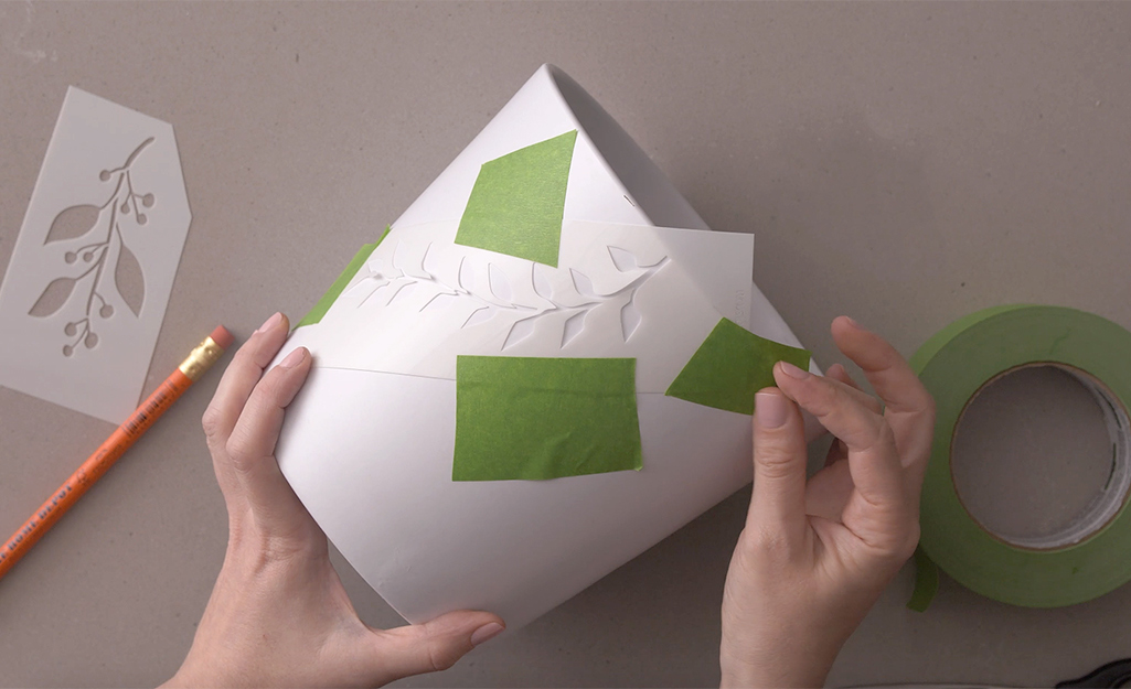Painter's tape is used to secure stencils to a plant pot. Painter's tape is used to secure stencils to a plant pot.