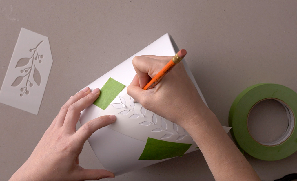 A person traces stencils onto a plant pot. A person traces stencils onto a plant pot.