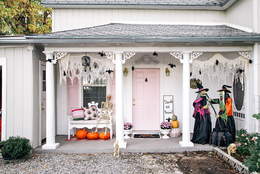 A front porch with a pink door is decorated with pumpkins and witches for Halloween. A front porch with a pink door is decorated with pumpkins and witches for Halloween.