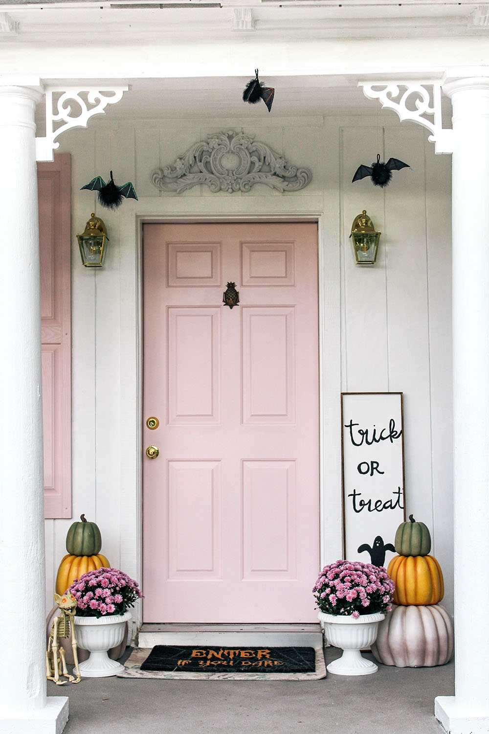 A pink front door with stacked pumpkins and planters with flowers. A pink front door with stacked pumpkins and planters with flowers.