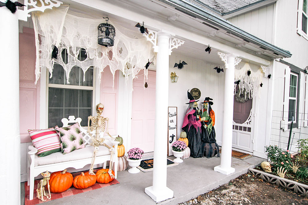 A front porch decorated with spider webs, witches, pumpkins, and a skeleton for Halloween. A front porch decorated with spider webs, witches, pumpkins, and a skeleton for Halloween.