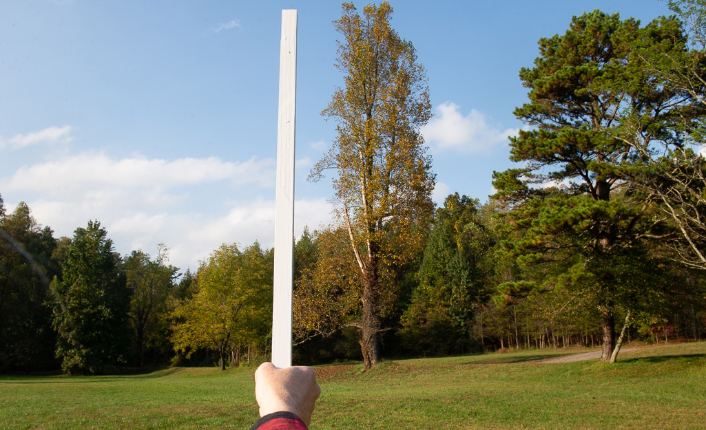 Someone using a yard stick to measure distance. Someone using a yard stick to measure distance.