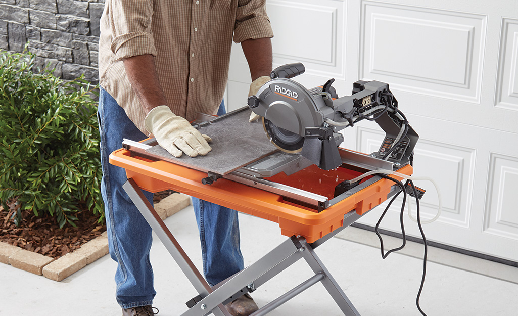 A person cuts tile with a wet saw.