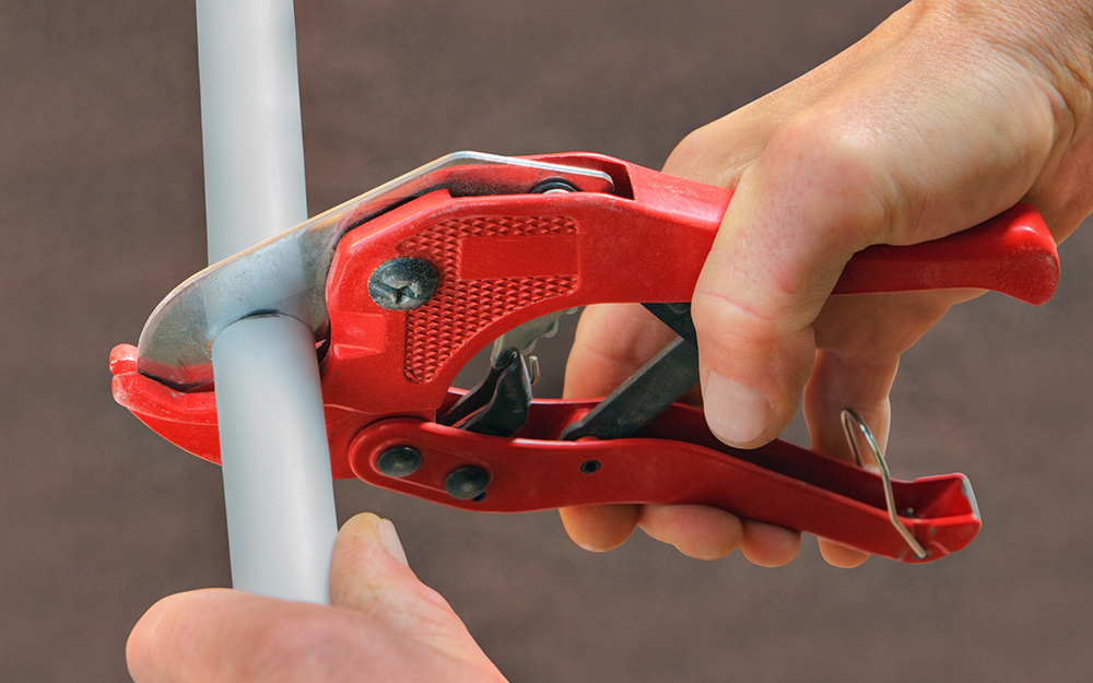 A person cuts pipe with scissor-type cutters.