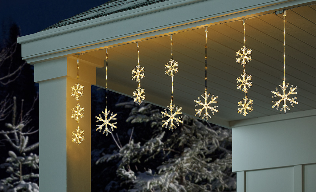 Snowflake Christmas lights hanging from the top of a home.