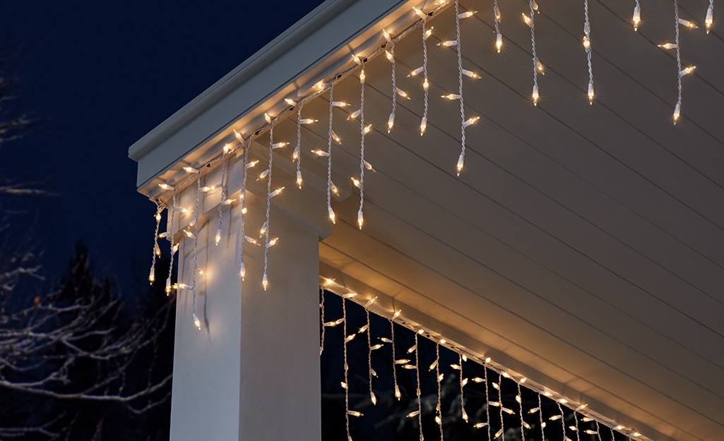 Icicle lights hanging from the top of a home at night.