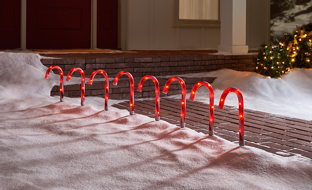 Candy cane lighting lining a snowy walkway.