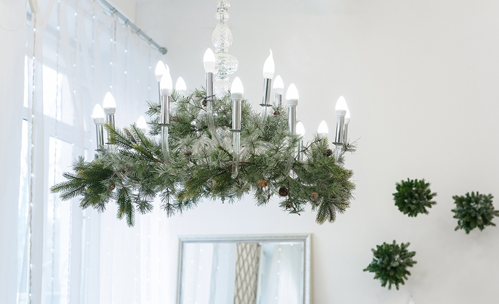 A chandelier covered in greenery and Christmas lights.