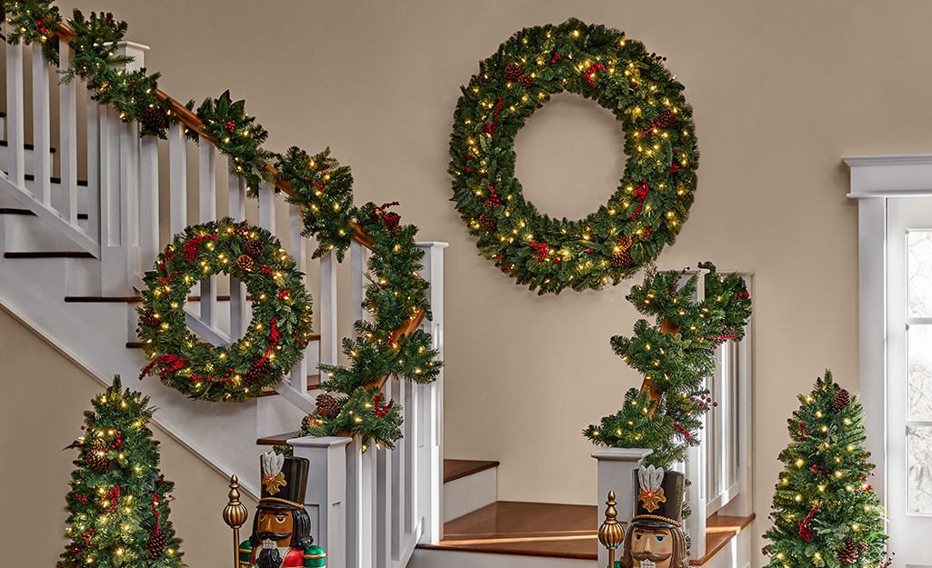Stairs in a home decorated with lighted Christmas garlands and wreaths.