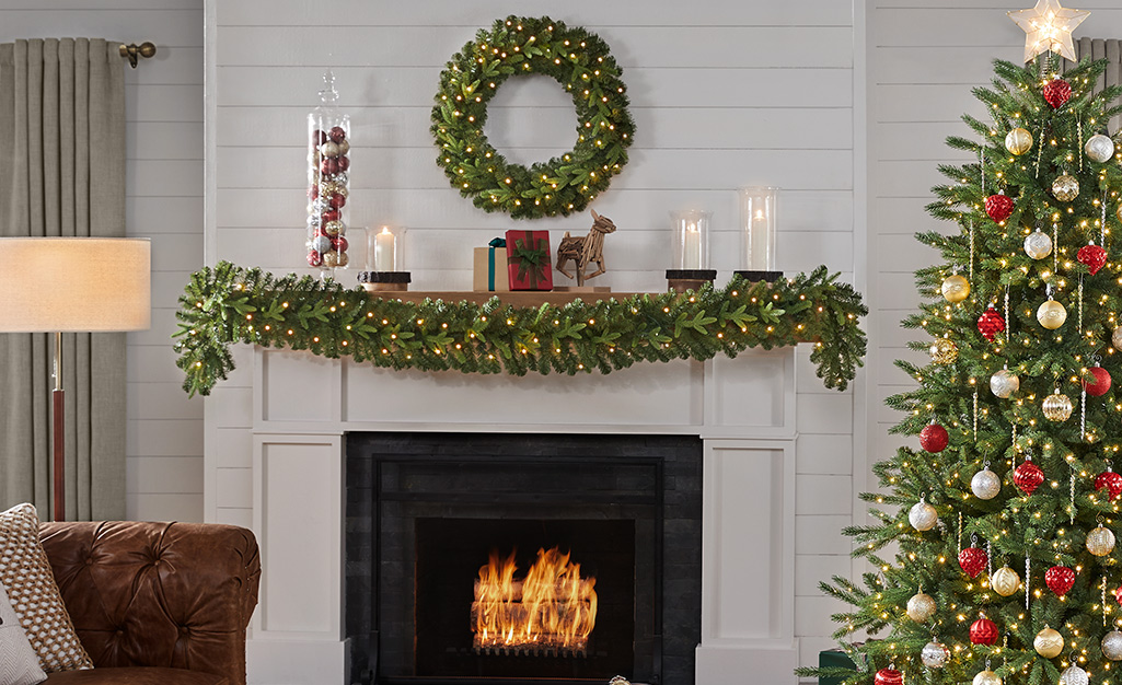 A mantel featuring evergreens and Christmas bulbs.