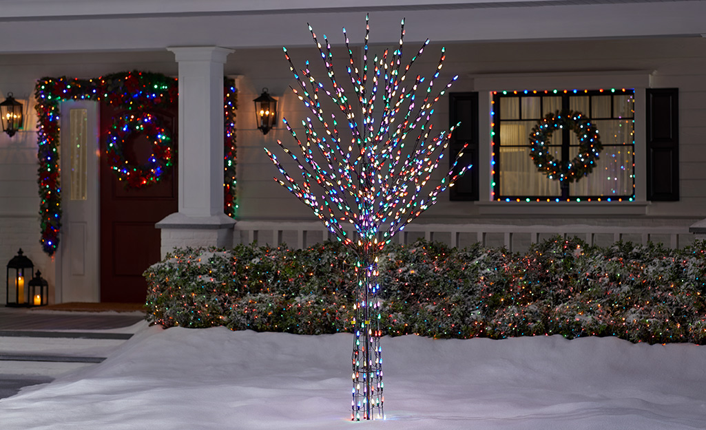 A multicolored Christmas tree light display in a front yard.