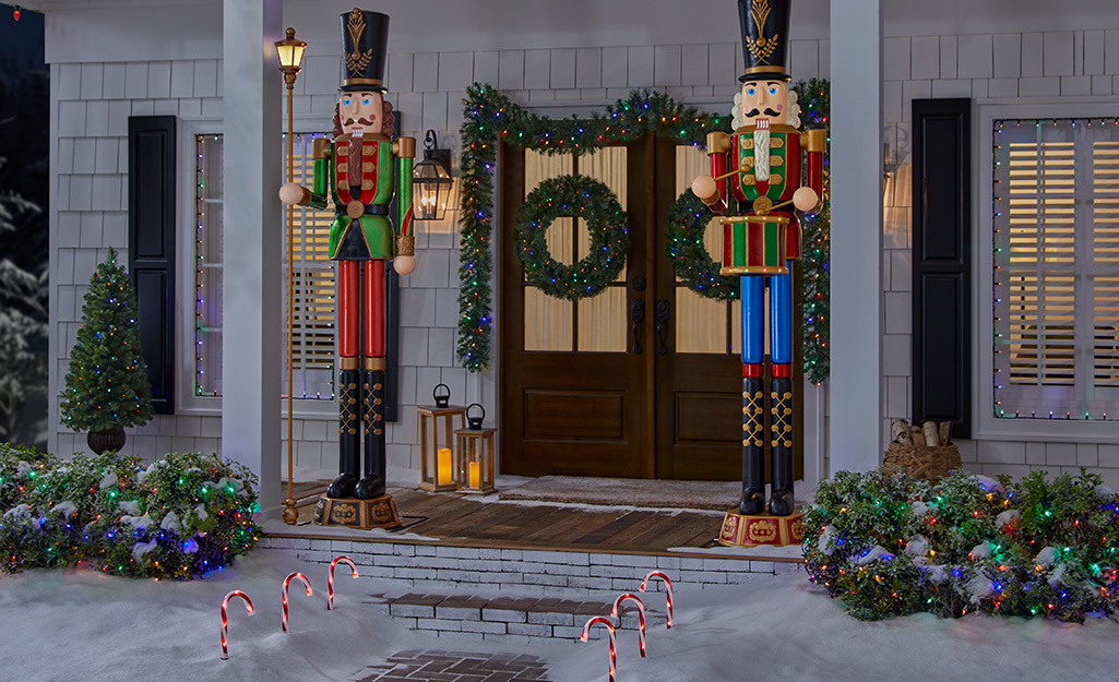 A pair of giant Christmas nutcrackers by a front door on a holiday porch