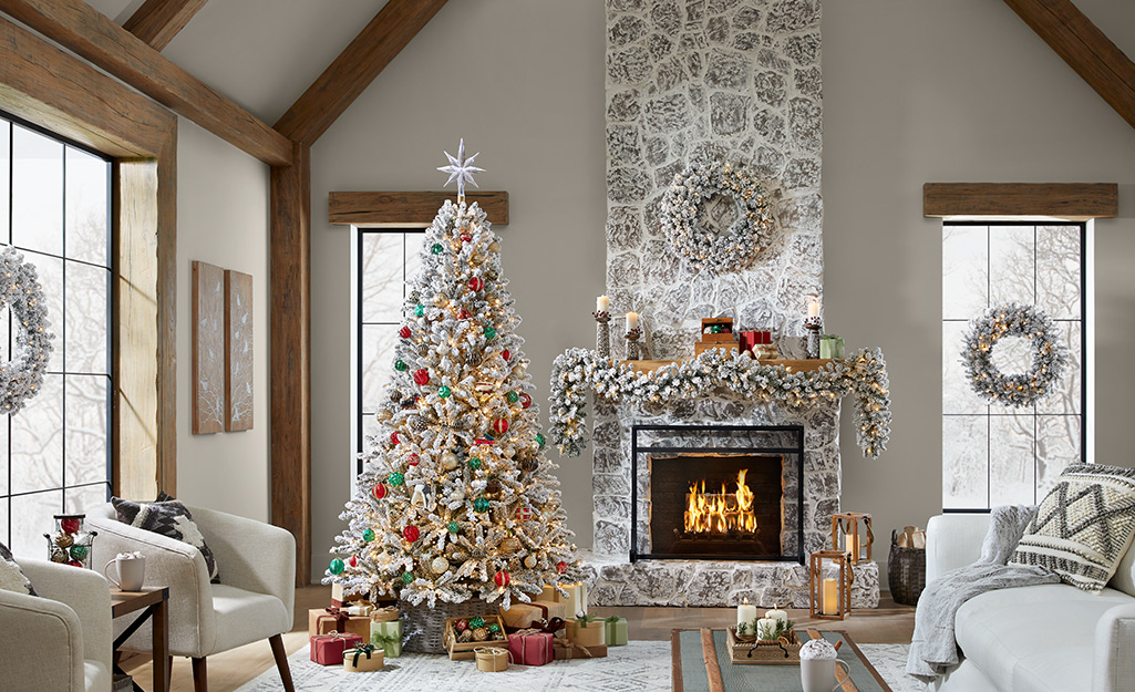 A Christmas living room display with a tree and a decorated fireplace mantel