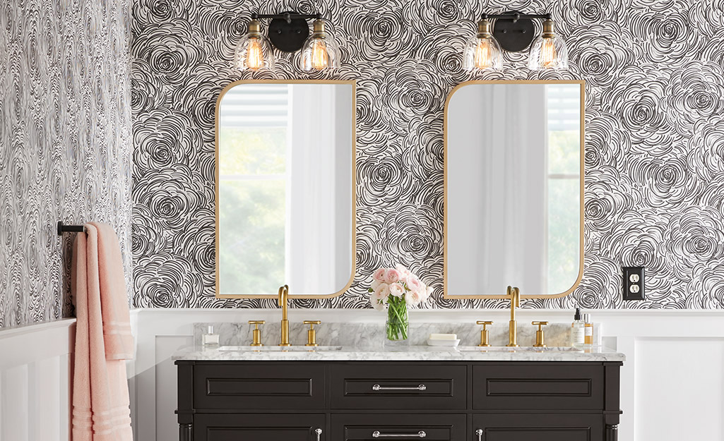 Double gold-finished metal vanity mirrors hang above a sink in a bathroom. 